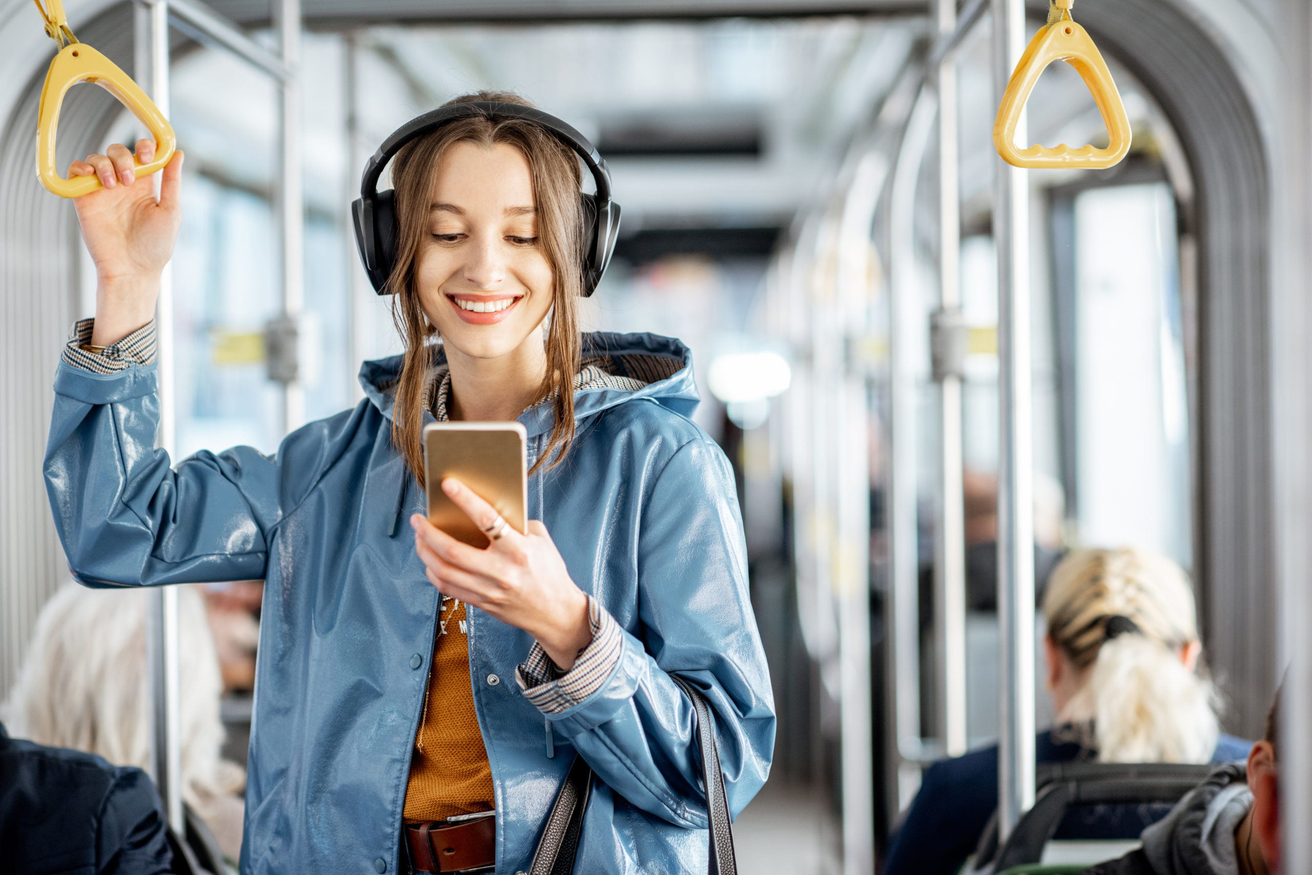Young,Woman,Passenger,Standing,With,Headphones,And,Smartphone,While,Moving